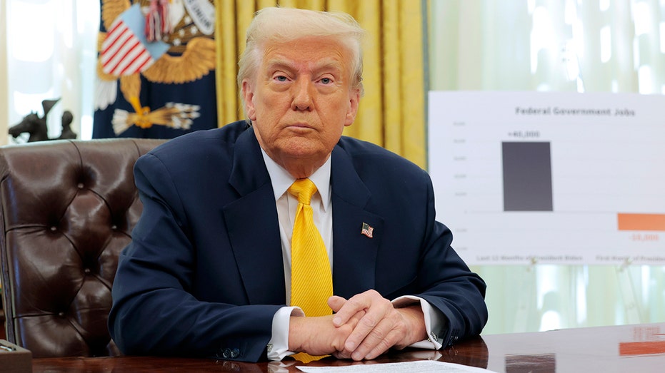 President Donald Trump at his Oval Office desk with a chart behind him